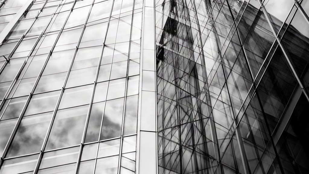 Fachada de edifício corporativo em vidro e aço com reflexos geométricos, representando o ambiente de precificação do crédito.